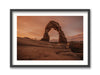 A framed print featuring Delicate Arch at Arches National Park, Utah, with a person included to show scale.