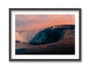 Framed artwork of a surfer riding a wave with a pink and orange sky.